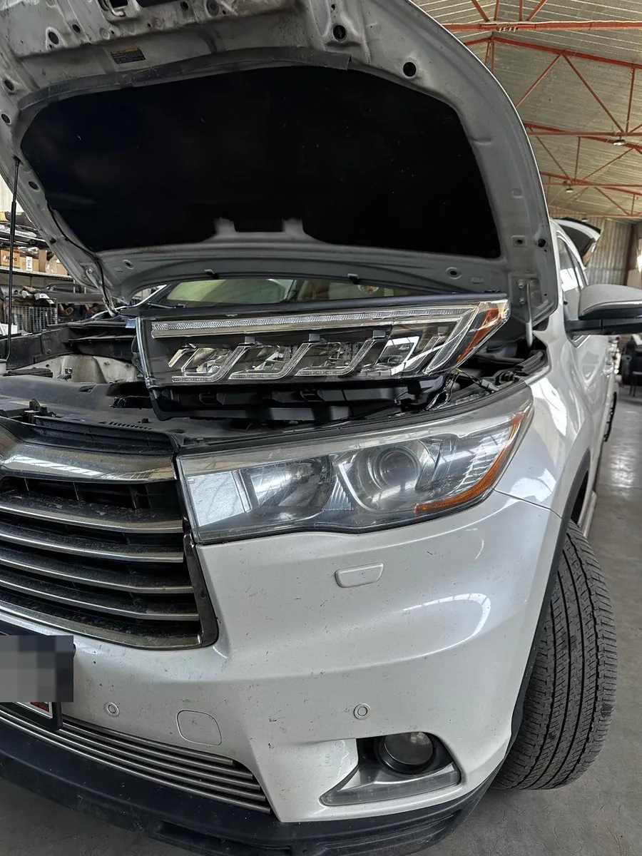 Toyota Highlander в цехе с открытым капотом, штатная оптика снята, детали обвеса подготовлены к установке
